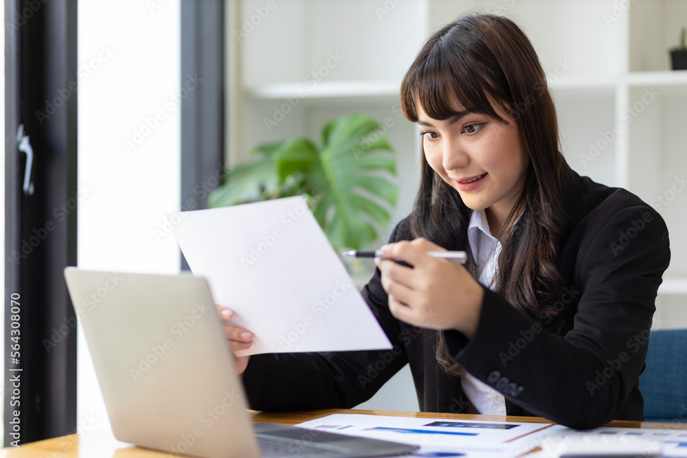 Businesswoman working with financial documents on laptop in office desk.