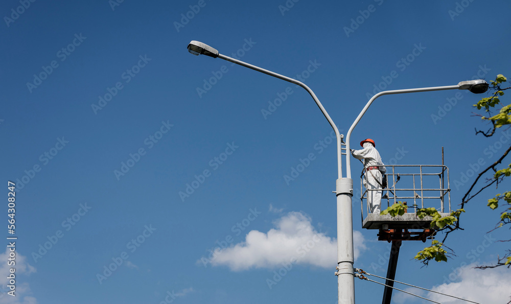 Men in cradle painting lamppost Men in cradle painting lamppost