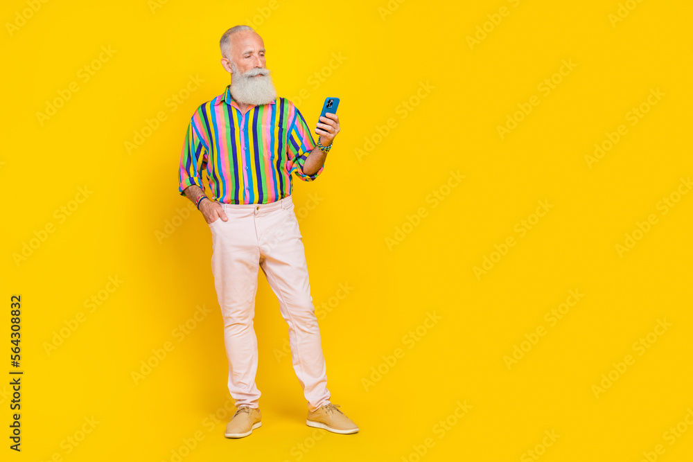 Fototapeta premium Full size portrait of confident serious aged man hold use telephone empty space isolated on yellow color background