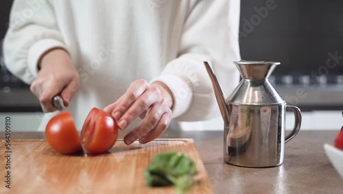 Donna taglia un pomodoro per una insalata photo