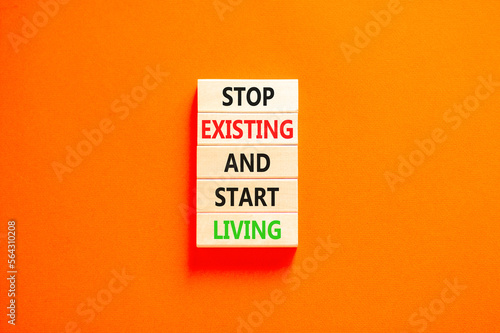 Stop existing start living symbol. Concept words Stop existing and start living on wooden blocks. Beautiful orange table orange background. Business Stop existing start living concept. Copy space.