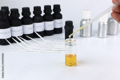 chemical beaker , flask is on white table with blotting paper , fragrance bottle and essential oil bottle are used to blend the nice scent for making perfume and candle by perfumer in the laboratory