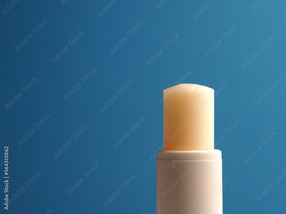 Close up of a lip balm stick on a blue background with space for your text Close up of a lip balm stick on a blue background with space for your text