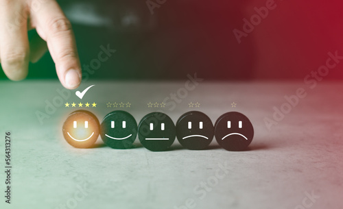 The best excellent services rating customer experience. Satisfaction survey concept. Hand of a customer chooses a smiley face on wood block cube and five star satisfaction.