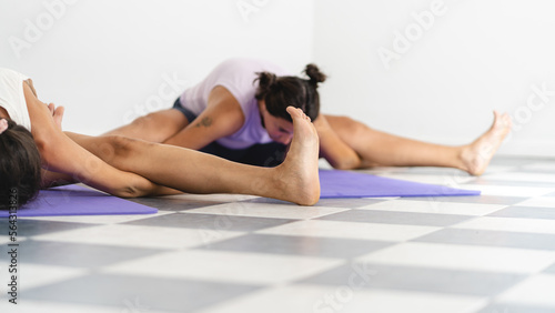 Close up image of two yogi women doing Tortoise pose, also known as Kurmasana. Selective focus with copy space
