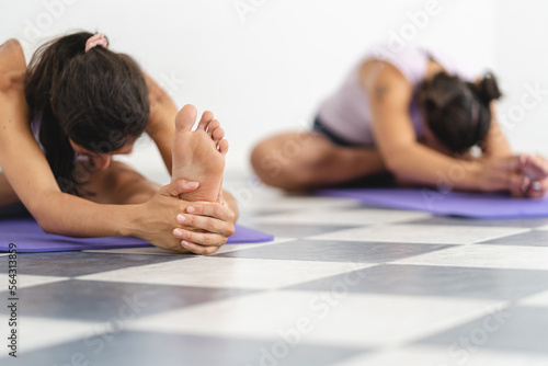 Close up shot of two women doing yoga while stretching with Janu Sirsasana pose. Selective focus with copy space