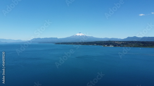 Aerial view of the volcano and mountains, on the shore of a lake in summer, with the city in the distance.