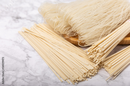 Rice noodles.Noodles with rice flour in a wooden plate on a white marble background.Close-up. Place for text. Copy space.