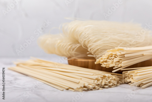 Rice noodles.Noodles with rice flour in a wooden plate on a white marble background.Close-up. Place for text. Copy space.