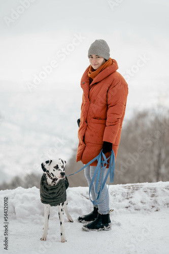 Warm angezogene Frau mit jungen Dalmatiner im Schnee während des Winters mit Ausblick auf Heidelberg