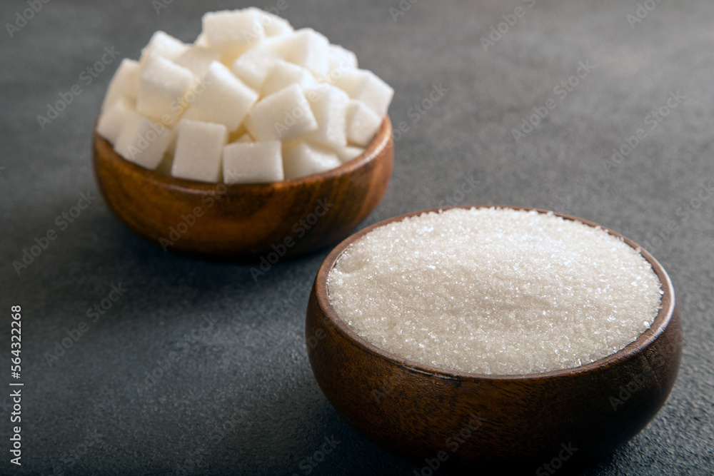 Cube sugar and granulated sugar on dark background Cube sugar and granulated sugar on dark background