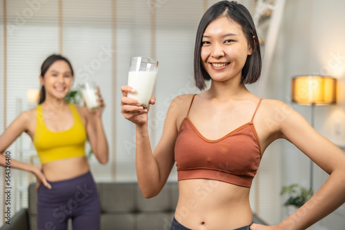 Attractive fitness asian woman finishing workout and drinking protein milk shake vitamins after training at home. Bodybuilding. Healthy lifestyle.