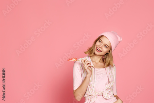 blonde woman holding candy on pink background.
