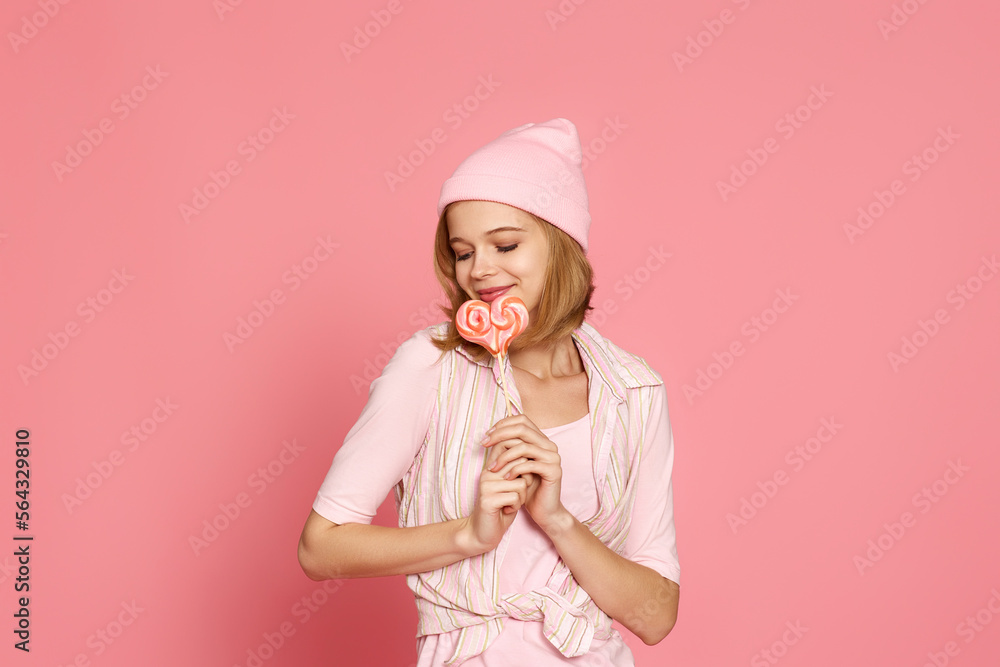 blonde woman holding candy on pink background. blonde woman holding candy on pink background.
