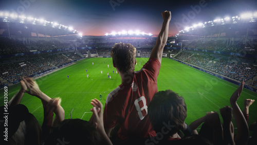 Establishing Shot of Fans Cheer for Their Favorite Team on a Stadium During Soccer Championship Match. Teams Play, Crowds of Fans Celebrate Victory and Goal. Live Football Cup Tournament Concept