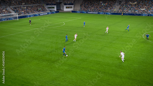 Soccer Football Championship Stadium with Crowd of Fans: Blue Team Forward Attacks, Dribbles, White Team Defending The Goals, Ready To Counterattack. Sports Channel Broadcast Television. High Angle. © Gorodenkoff