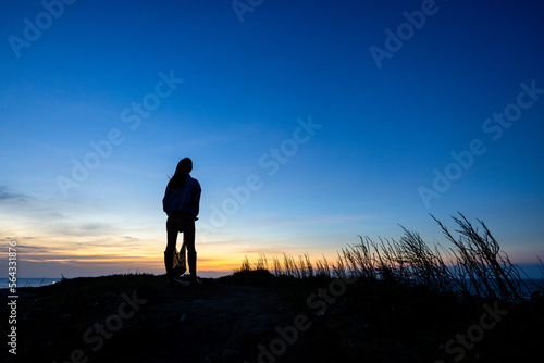 Silhouette of woman stand at the top of the mountain in the evening © leungchopan