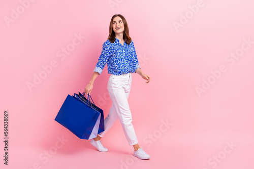 Full length photo of excited pretty lady wear print shirt holding shoppers looking empty space isolated pink color background