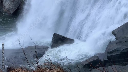 Tight view of a misty mountain waterfall breaking onto jagged rocks