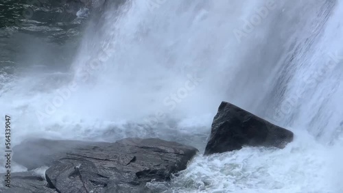 Misty mountain waterfall crashing onto jagged rocks