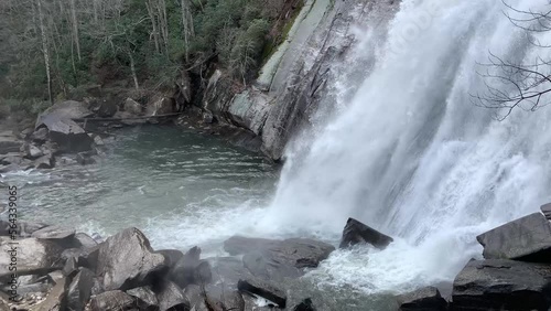 The turbulent rocky base of a misty mountain waterfall on a cloudy day