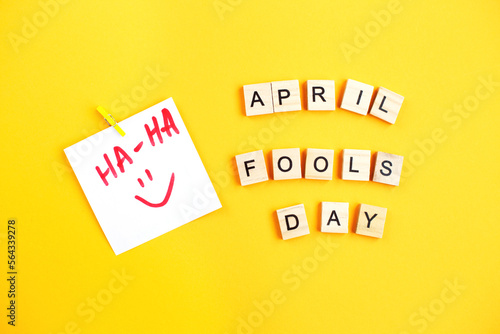 sticker with smiley and inscription april fools day made by wooden cubes on yellow background.
