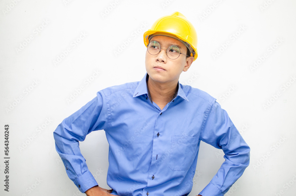 Asian construction worker in blue shirt and yellow safety helmet is seriously thinking with a wondering and thinking gesture and expression. Asian construction worker in blue shirt and yellow safety helmet is seriously thinking with a wondering and thinking gesture and expression.