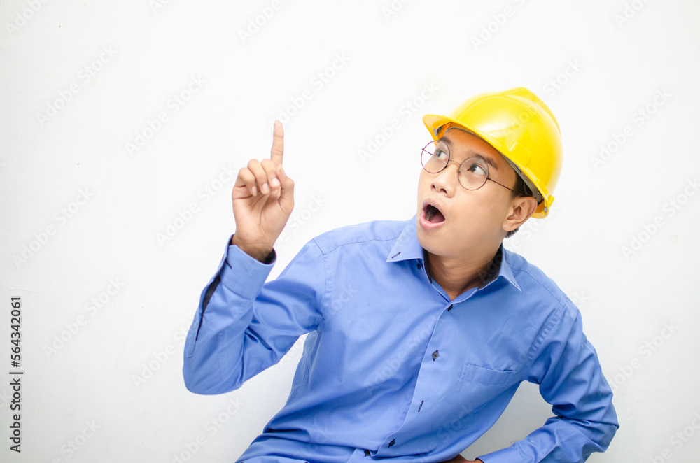 A happy, shocked asian consrtuction worker in blue shirt and yellow safety helmet pointing finger and presenting something ads. A happy, shocked asian consrtuction worker in blue shirt and yellow safety helmet pointing finger and presenting something ads.