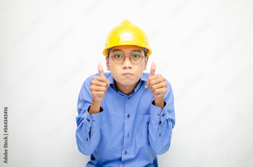 Young Asian male construction worker or engineer smiling happily and giving thumbs up as compliment. Young Asian male construction worker or engineer smiling happily and giving thumbs up as compliment.