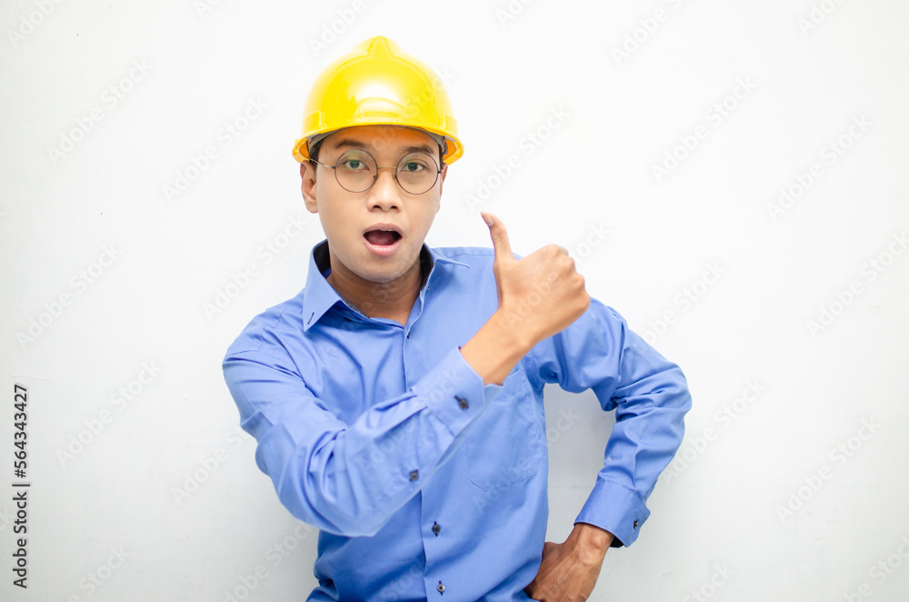 Young Asian male construction worker or engineer smiling happily and giving thumbs up as compliment. Young Asian male construction worker or engineer smiling happily and giving thumbs up as compliment.