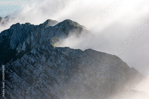 the peaks of the rocky ridge of the Piatra Craiului massif in the Romanian Carpathians shrouded in fog photo