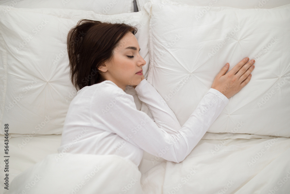 Woman sleeping in double bed with hand on empty pillow Woman sleeping in double bed with hand on empty pillow