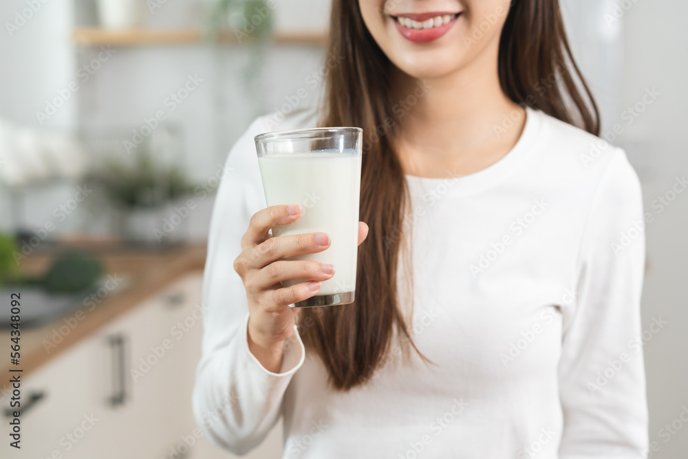 Health care, pretty asian young woman, girl drinking a glass of white fresh, dairy milk for calcium, vitamin wholesome good nutrition in morning at kitchen home. lifestyle, product healthy people.