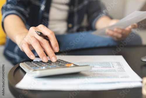 Deduction planning concept. Asian young woman hand using calculator to calculating balance prepare tax reduction income, cost budget expenses for pay money form personal Individual Income Tax Return. photo
