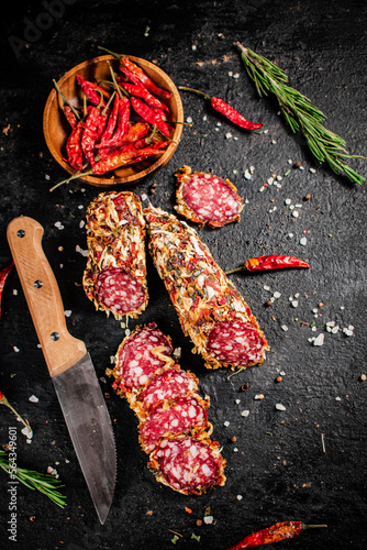 Pieces of salami sausage with dried chili peppers and rosemary. 
