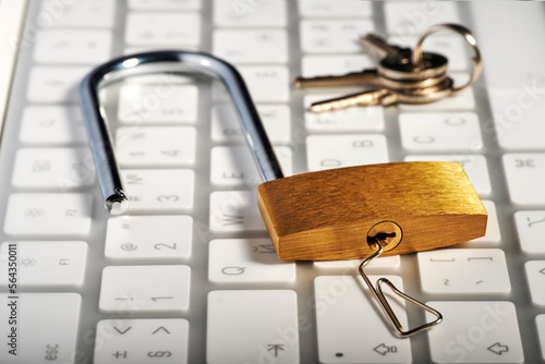 The concept of a strong password and protecting computers from hacking, the padlock is opened with a paper clip, keyboard and keys in the background