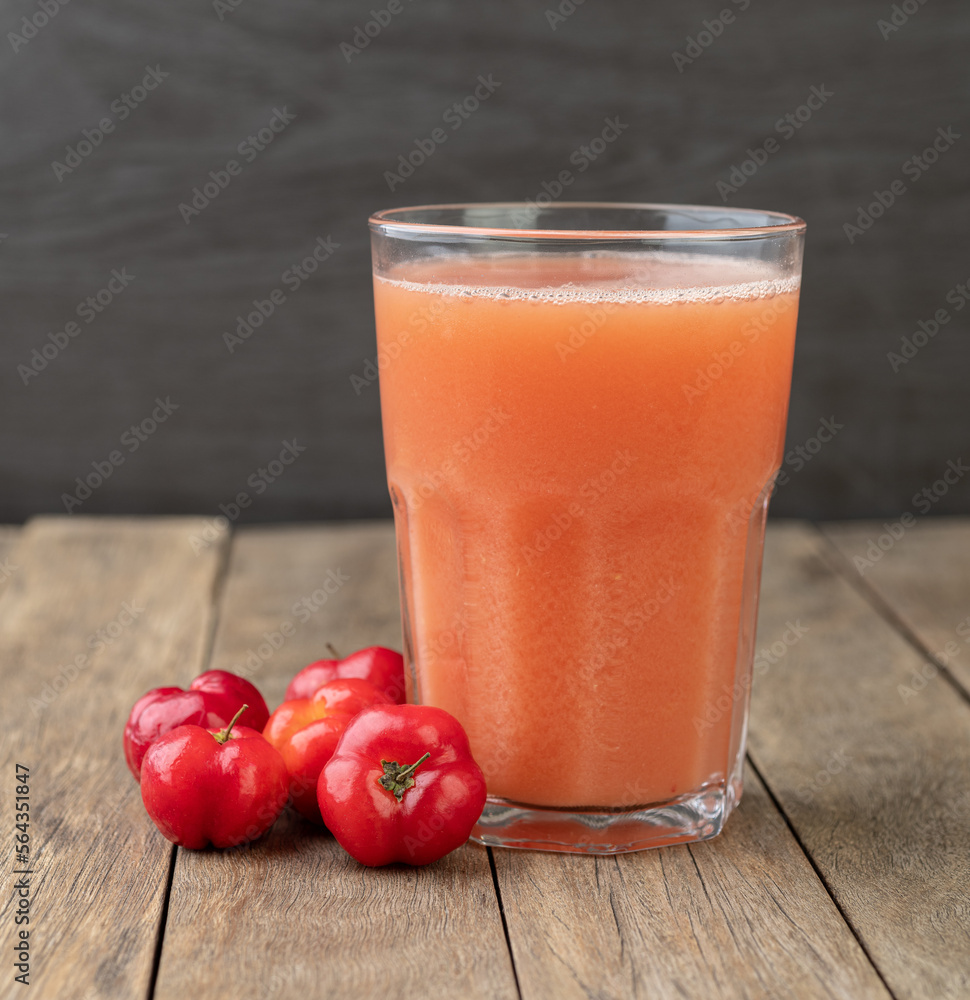 Acerolas or Barbados Cherries juice with fruits over wooden table Acerolas or Barbados Cherries juice with fruits over wooden table