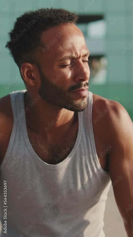 VERTICAL VIDEO: Young bearded male athlete is resting after training sitting on bench VERTICAL VIDEO: Young bearded male athlete is resting after training sitting on bench