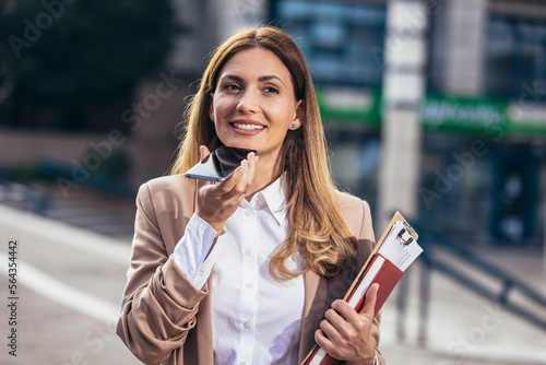 Slika na platnu Corporate woman records voice message on smartphone, talks into microphone on mobile phone