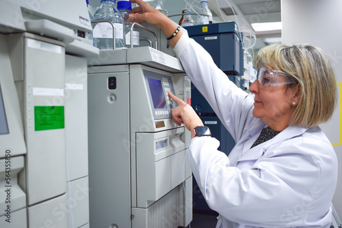 Wallpaper Mural Smiling mature scientist woman wearing lab coat working with electronic machine in research laboratory for diagnostic and analysis of diseases happy to find a health treatment at modern work center Torontodigital.ca