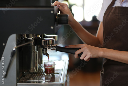 Barista make coffee latte art with espresso machine in cafe vintage color tone. Professional coffee machine making espresso in a cafe. Preparation of freshly ground coffee.