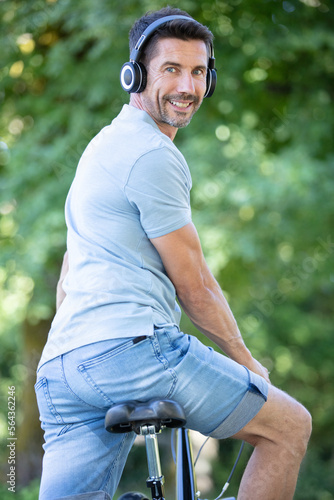back view of a man wearing earphones with a bicycle