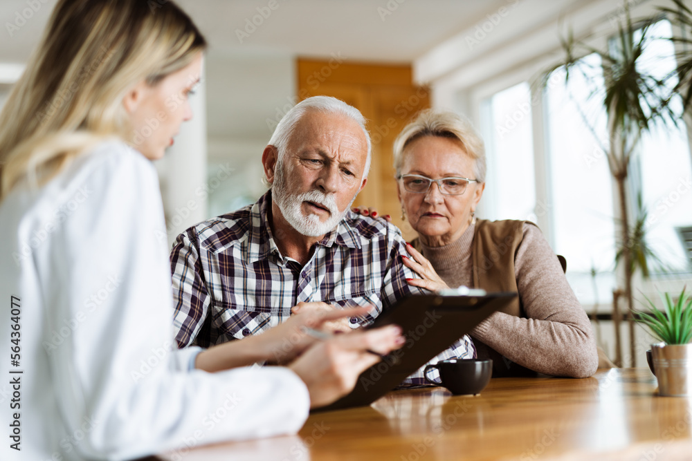 Mature couple looking at their plan of care and medications with female nurse at home - obrazy, fototapety, plakaty 