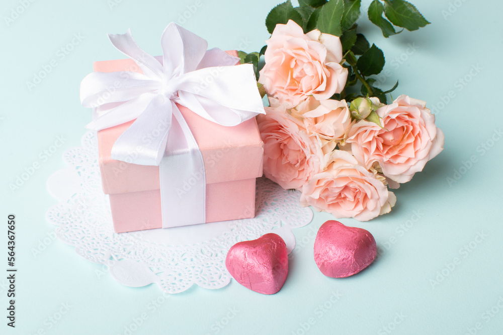 A gift with a bouquet of flowers and a knitted heart on a light blue background. A gift with a bouquet of flowers and a knitted heart on a light blue background.