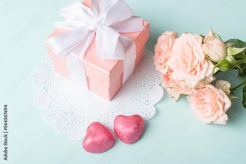 A gift with a bouquet of flowers and a knitted heart on a light blue background. An invitation for Valentine's Day. Space for copying. Flat position, top view A gift with a bouquet of flowers and a knitted heart on a light blue background. An invitation for Valentine's Day. Space for copying. Flat position, top view
