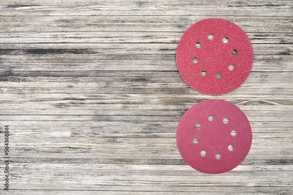 Round red sanding discs for orbital sander. Top view of adhesive sandpaper discs on a wooden background with copy space. Round red sanding discs for orbital sander. Top view of adhesive sandpaper discs on a wooden background with copy space.