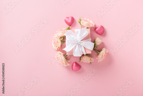 Valentine's Day background. A banner layout with a gift, roses and hearts on a light pink background with a space for text. © Irina Lesovaia