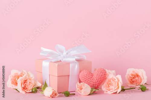 Pink gift box with a white bow and a bouquet of roses on a pink background © Irina Lesovaia