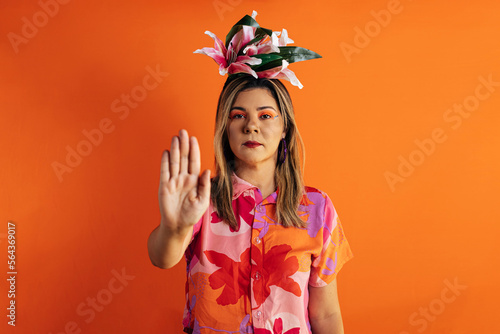 Young beautiful woman wearing carnival costume over color background making stop singing with palm of hand