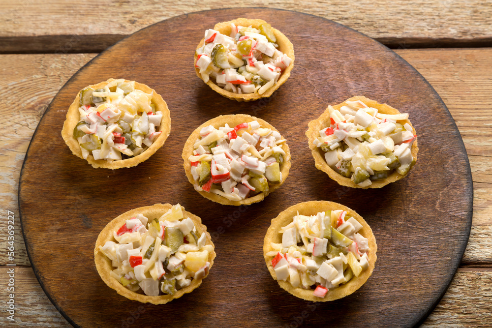 salad with shrimps in tartlets on a board on a wooden table. salad with shrimps in tartlets on a board on a wooden table.